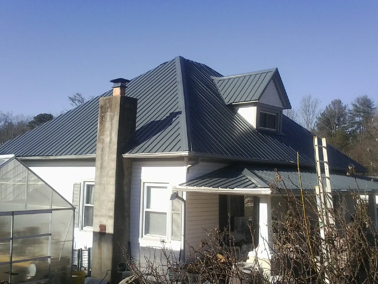 Dark blue standing seam metal roof on a white farmhouse with dormer — Slate & Tile Roof Repair by Roofing Brothers in Yucaipa