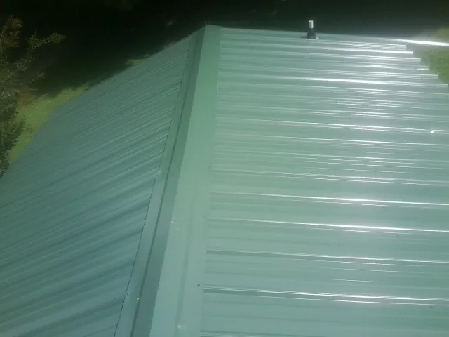 New green metal panels meeting at the ridge of a roof — Flat Roof Repair work by our crew in Yucaipa