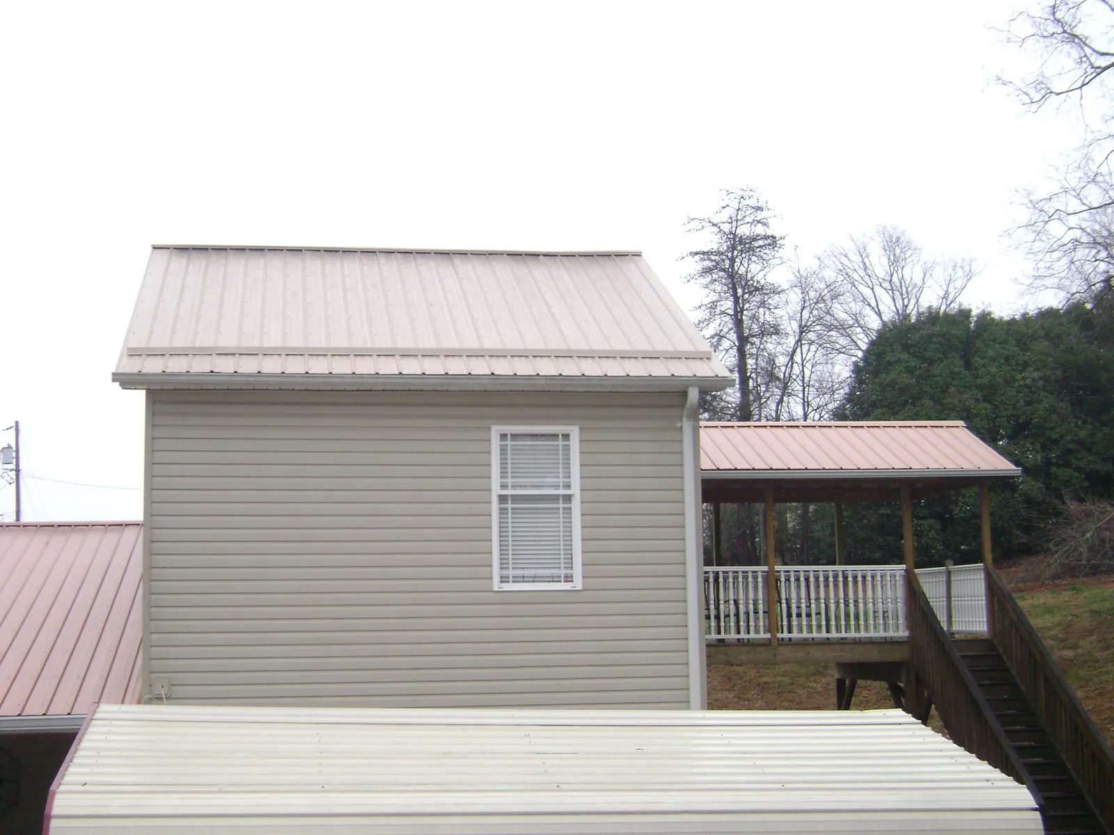 Tan metal roofs on a two story addition and attached porch, from a Roof Replacement job in Yucaipa